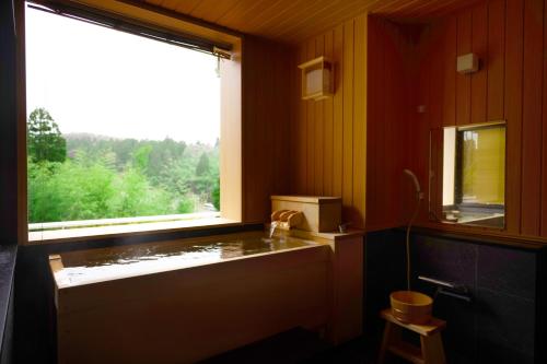 a bathroom with a window and a sink and a tub at Notoya in Komatsu