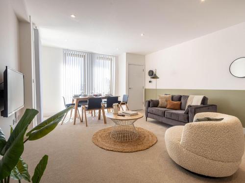 een woonkamer met een bank en een tafel bij Modern Apartments with Balcony in Merton near Wimbledon by Sojo Stay in Mitcham