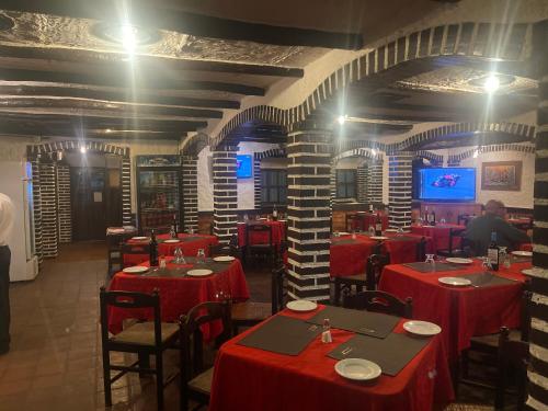 Hotel brisas del mar 2022 في Catia La Mar: مطعم بطاولات حمراء وكراسي وتلفزيون