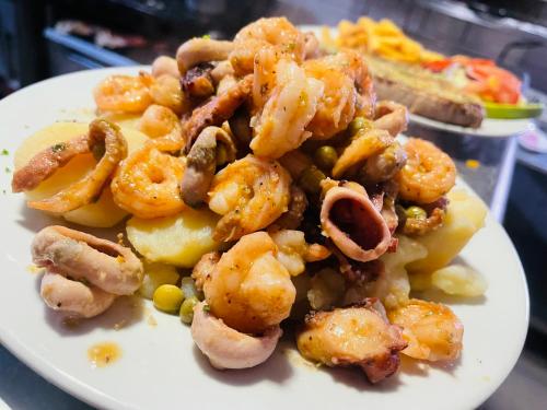 a plate of shrimp and vegetables on a table at Hotel brisas del mar 2022 in Catia La Mar
