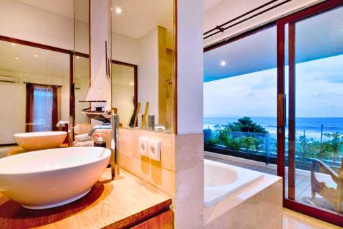 a bathroom with a large white tub and a large window at Angkasa 5 BR Beachfront Villa JU31 in Keramas