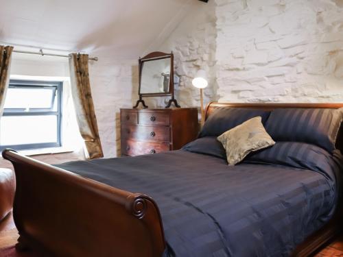 een slaapkamer met een bed en een stenen muur bij Bwthyn Afon in Blaenau-Ffestiniog