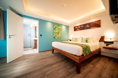 a bedroom with a bed and a blue wall at Maitai Express Tahiti in Papeete