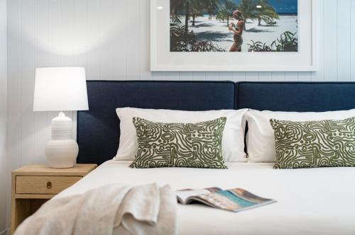 ein Schlafzimmer mit einem weißen Bett mit Kissen und einem Bild in der Unterkunft Jacaranda Noosa in Noosa Heads