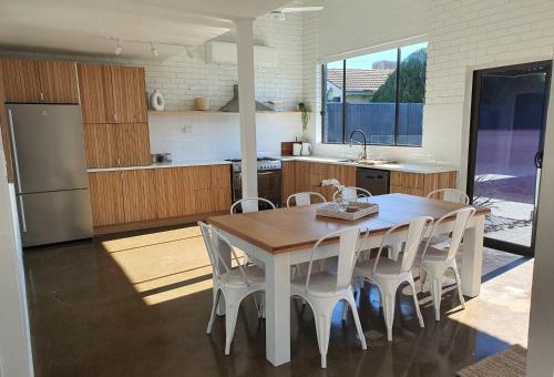 a kitchen with a wooden table and white chairs at Perfect Large Multi Family Accommodation in Yarrawonga
