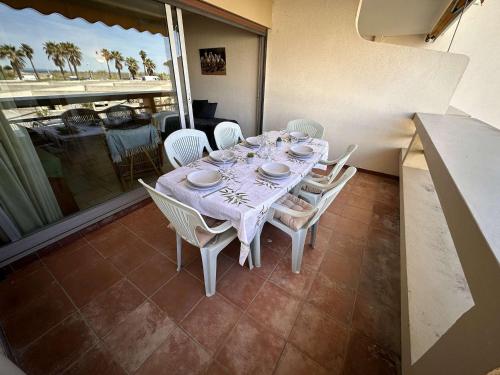 une table avec des chaises blanches et un chiffon de table blanc dans l'établissement Marina 2 pièces bord de mer, parking privé, 5 pers - FR-1-731-77, au Grau-du-Roi