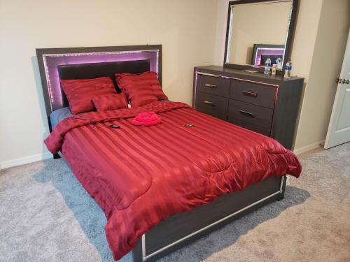 Schlafzimmer mit einem Bett mit einer roten Bettdecke und einem Spiegel in der Unterkunft Troy@Kissimme in Kissimmee