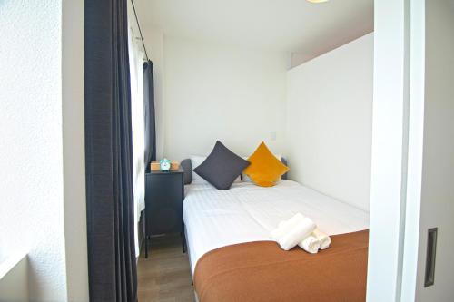 a small bedroom with a bed with orange and blue pillows at 旅タイム・西長堀　駅まで徒歩6分　USJ電車8分 in Osaka