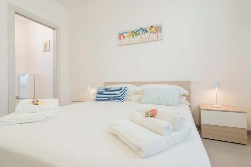 una camera da letto bianca con un grande letto bianco con asciugamani sopra di Guest House MareLuna a Carloforte