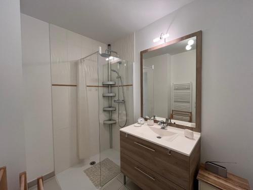 une salle de bain avec un lavabo, une douche et un miroir dans l'établissement Arcachon Centre : T2 avec Parking, Loggia et Proche Plage - FR-1-319-566, à Arcachon