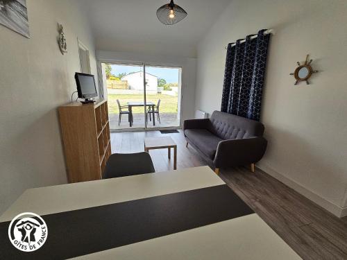 un salon avec un canapé et une table dans l'établissement Gîte 2 pers. proche plages et Marais Poitevin, terrasse couverte, tout inclus - FR-1-426-551, à Saint-Michel-en-lʼHerm