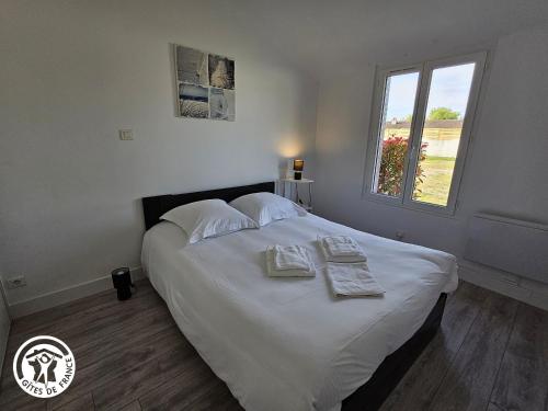 une chambre avec un lit blanc avec des serviettes dessus dans l'établissement Gîte 2 pers. proche plages et Marais Poitevin, terrasse couverte, tout inclus - FR-1-426-551, à Saint-Michel-en-lʼHerm
