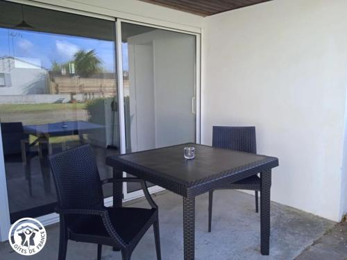 une table noire et des chaises sur une terrasse dans l'établissement Gîte cosy pour 2, proche plages et Marais Poitevin, avec terrasse privative à Saint-Michel-en-l'Herm - FR-1-426-549, à Saint-Michel-en-lʼHerm