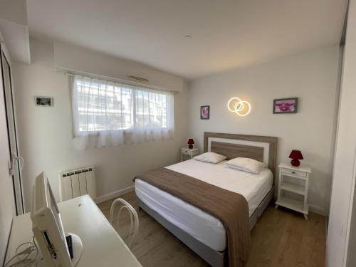 une chambre avec un lit et un bureau avec un ordinateur dans l'établissement Appartement T3 avec Terrasse et Garage en Plein Centre de Royan, Proche Plages et Marché - FR-1-71-107, à Royan