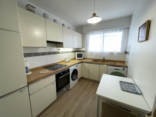 une cuisine avec des armoires blanches et une laveuse et une sécheuse dans l'établissement Appartement T3 avec Terrasse et Garage en Plein Centre de Royan, Proche Plages et Marché - FR-1-71-107, à Royan