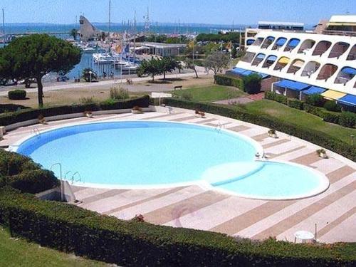 une grande piscine devant un immeuble dans l'établissement Appartement 3 Pièces, Piscine Privée, Proche Plage - Port Camargue - FR-1-731-74, au Grau-du-Roi