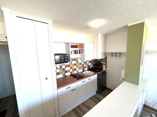 une petite cuisine avec un évier et un micro-ondes dans l'établissement Studio face à la mer, 3 couchages, balcon, parking, à 10m de la plage - Port-la-Nouvelle - FR-1-229C-98, à Port-la-Nouvelle