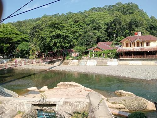 un cuerpo de agua con una casa en el fondo en Fun Family Guest House n Jungle Tour en Bukit Lawang