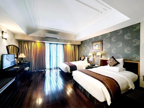 a hotel room with two beds and a television at Rex Hotel in Ho Chi Minh City