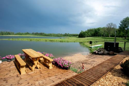 a wooden deck with a picnic table and a lake at Atpūtas māja "Rūdupji" in Gulbene