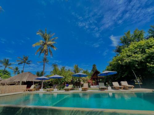 a swimming pool with chairs and umbrellas at Gita Gili Bungalow in Gili Air
