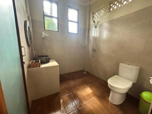baño con aseo y lavabo y ventana en Nirwa Ubud Karma, en Ubud