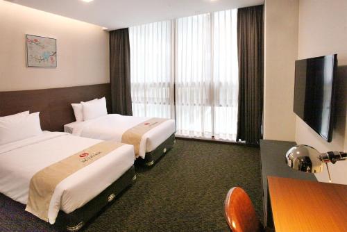 a hotel room with two beds and a flat screen tv at Hotel Skypark Kingstown Dongdaemun in Seoul