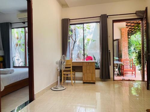 a bedroom with a bed and a desk with a window at Mui Ne Garden Hotel and Kite School in Mui Ne