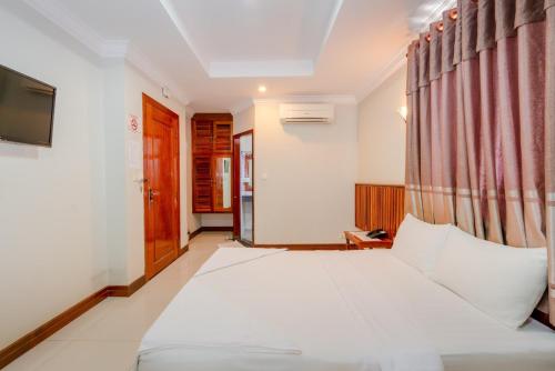 een slaapkamer met een groot wit bed en een gordijn bij Holiday Hotel in Kampong Speu
