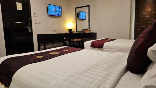 ein Hotelzimmer mit 2 Betten und einem Spiegel in der Unterkunft Tara Angkor Hotel in Siem Reap