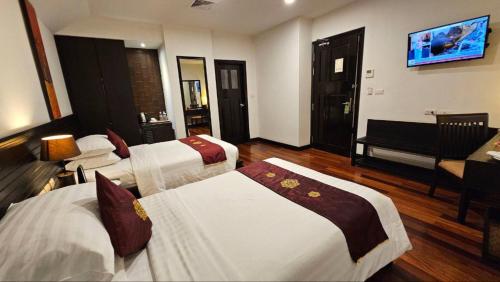 a hotel room with three beds and a piano at Tara Angkor Hotel in Siem Reap