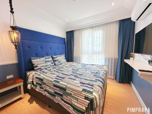 a bedroom with a large bed with a blue headboard at Jomtien Beach, Pattaya - Seven Seas Côte d'Azur in Na Jomtien