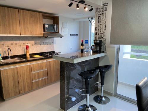 a kitchen with a counter and two bar stools at Apartamento Exclusivo - Caribe Campestre Coveñas in Coveñas