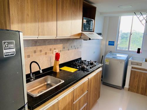 a kitchen with a sink and a stove and a refrigerator at Apartamento Exclusivo - Caribe Campestre Coveñas in Coveñas
