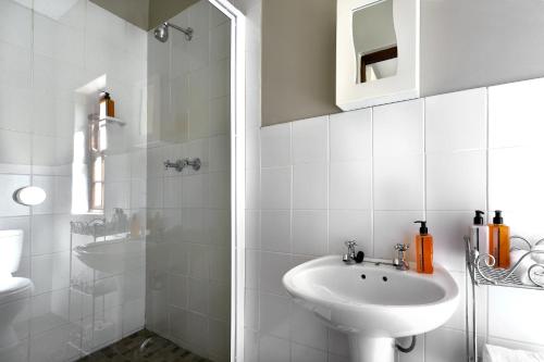y baño blanco con lavabo y ducha. en La Gratitude Self catering cottage, en Franschhoek