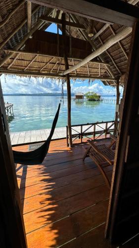 a hammock on a porch with a view of the water at Nyande Raja Ampat in Pulau Mansuar