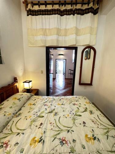 a bedroom with a bed with a floral bedspread and a mirror at Rinconada in Taxco de Alarcón