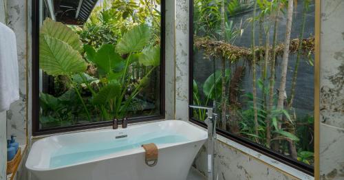 a bath tub in a room with a large window at Amara Private Villa in Siem Reap