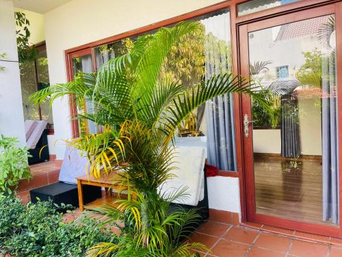 a house with a palm tree in front of a door at Mui Ne Garden Hotel and Kite School in Mui Ne