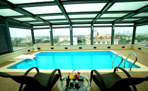 a large swimming pool with a glass table and chairs at Skylark Hotel & Spa Ha Noi in Hanoi