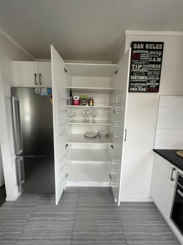 a kitchen with white cabinets and a refrigerator at Ellerslie central in Auckland