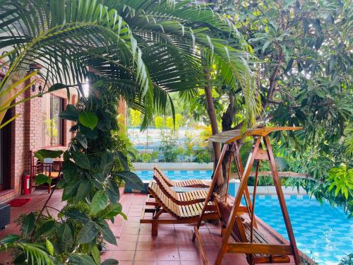 a patio with chairs and a palm tree next to a pool at Mui Ne Garden Hotel and Kite School in Mui Ne