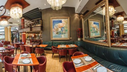 a restaurant with tables and chairs and paintings on the wall at Pelister Skopje in Skopje