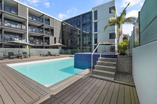 a swimming pool in front of a building at Central Style The Mount with Pool Spa Gym in Mount Maunganui