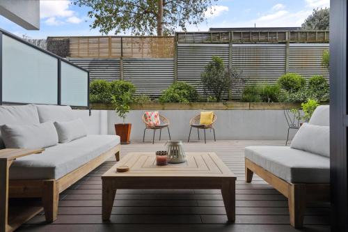 a patio with two couches and a coffee table at Central Style The Mount with Pool Spa Gym in Mount Maunganui
