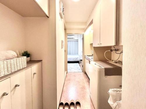 a small kitchen with white cabinets and a washer and dryer at Ikebukuro Sugamo 駅近 A4 in Tokyo