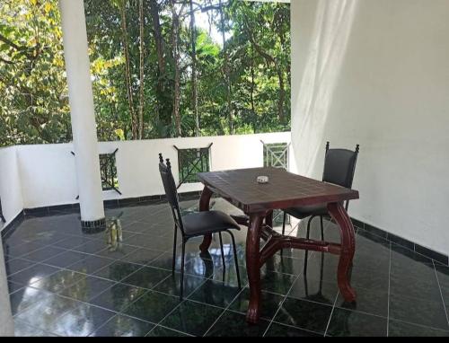 einen Holztisch und Stühle auf einer Terrasse mit einem Fenster in der Unterkunft 4Seasons Holiday Home in Ratnapura