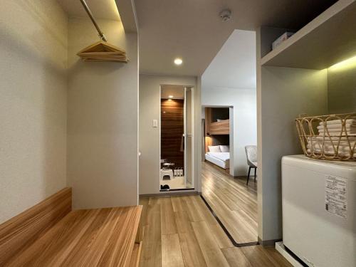 a room with a hallway with a refrigerator and a bedroom at Rakuyado Shinimamiya in Osaka