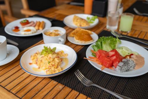 The Mangrove Phuket by Blu Monkey في شاطئ بنوا: طاولة خشبية عليها أطباق طعام