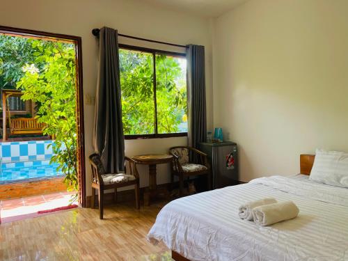 a bedroom with a bed and a table and a window at Mui Ne Garden Hotel and Kite School in Mui Ne